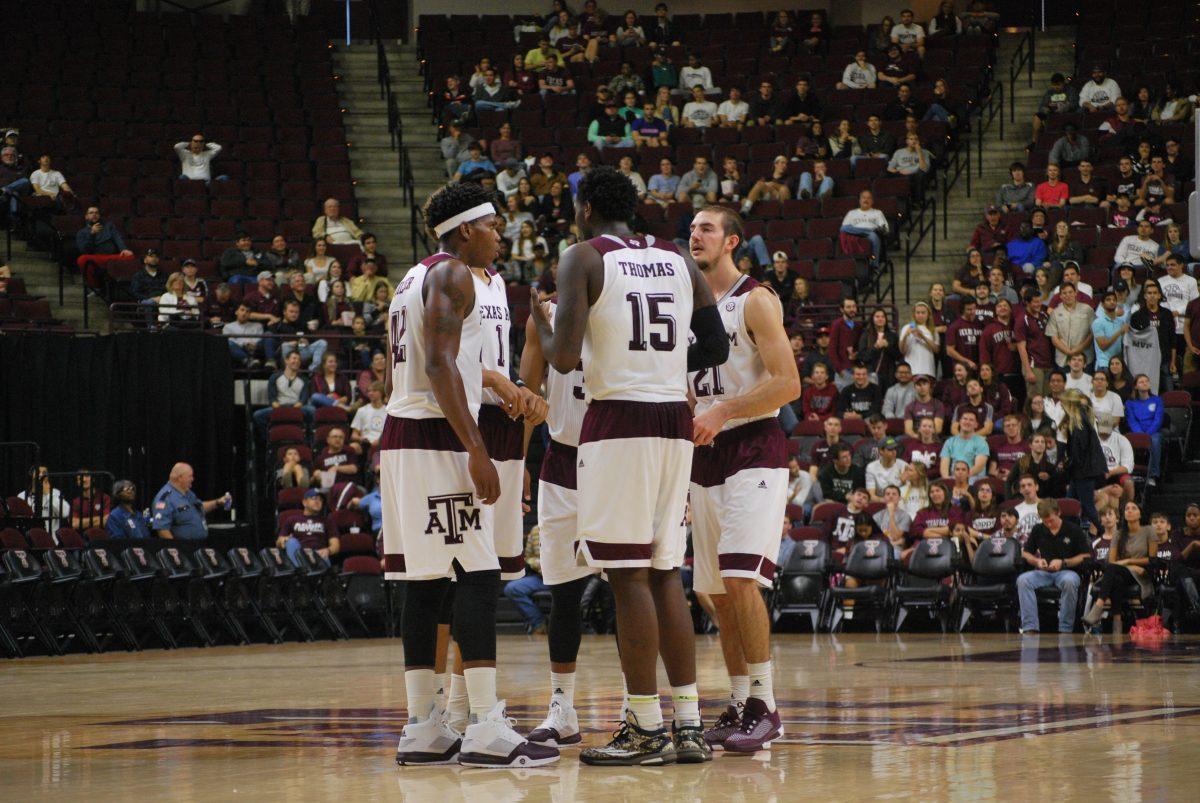 Aggie basketball players gather at center court. 