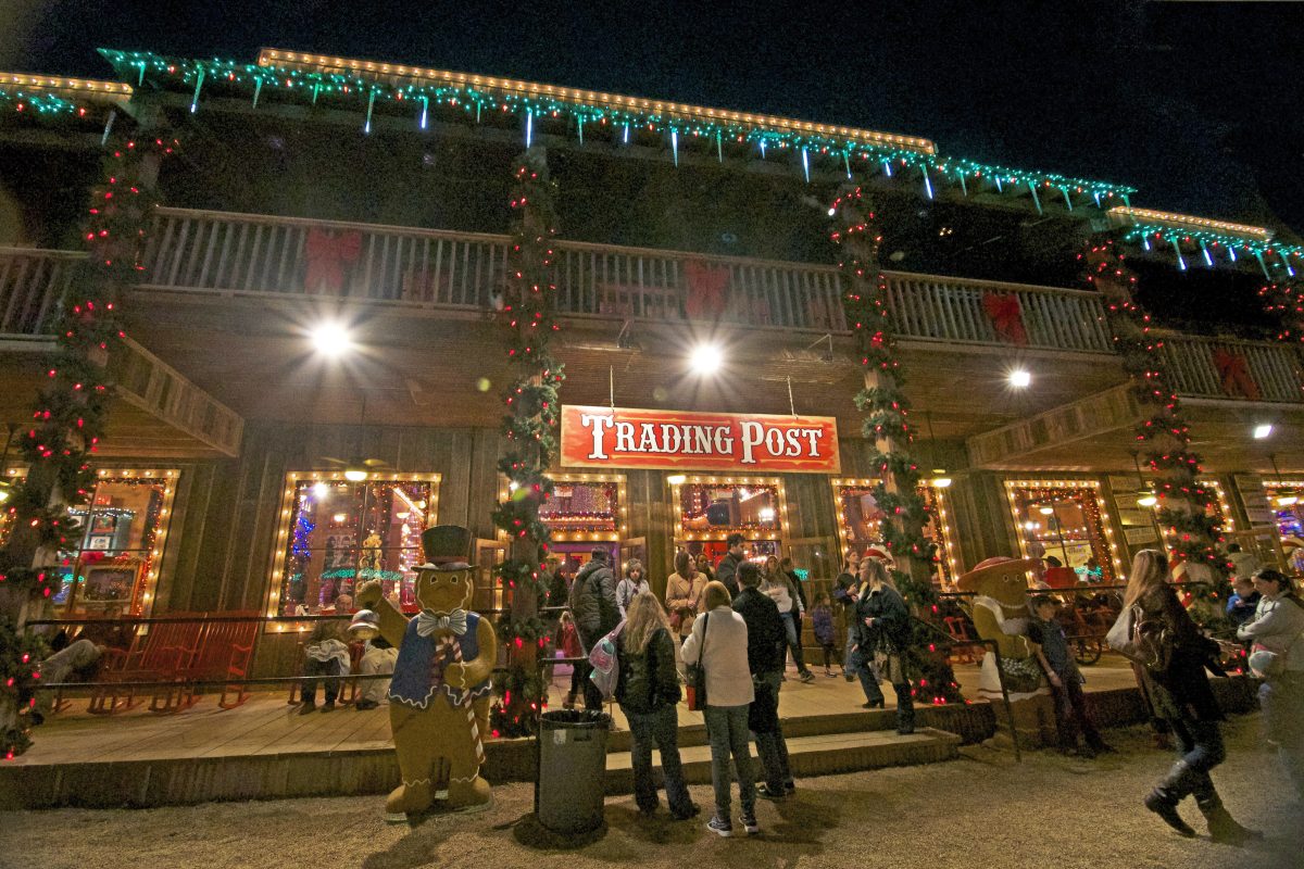 Outside of the Trading Post at Santa's Wonderland, people stand around festive decorations and lights.&#160;