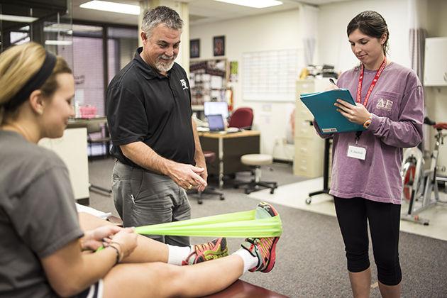 Ashley Taylor and Emily Chapman, kinesiology majors, volunteer under physical therapist, Kyle Greeley, at the Beutel clinic to gain experience in the field