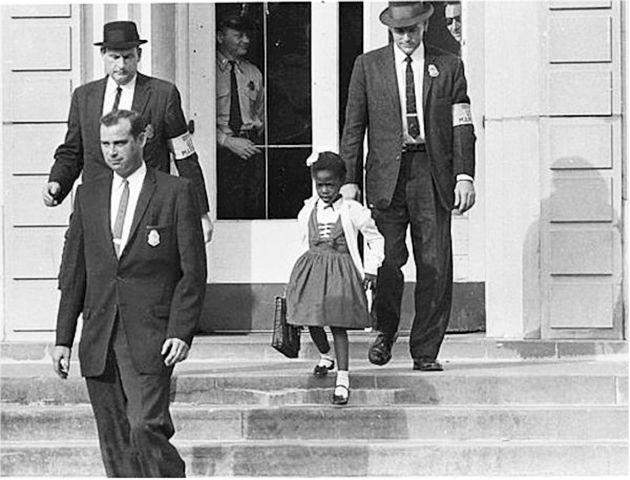 A+young+Ruby+Bridges+is+escorted+down+the+stairs+on+her+first+day+at+an+otherwise+all-white+school+in+1960.