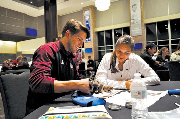 Finance senior Duncan Mulleady and finance junior Maddy Stulce write with the prosthetic that they had constructed.