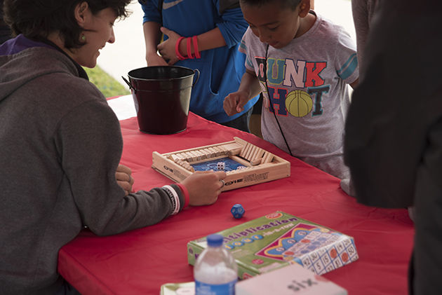 A women from Mathnasium plays a boy in a dice game during the Earth Day festival