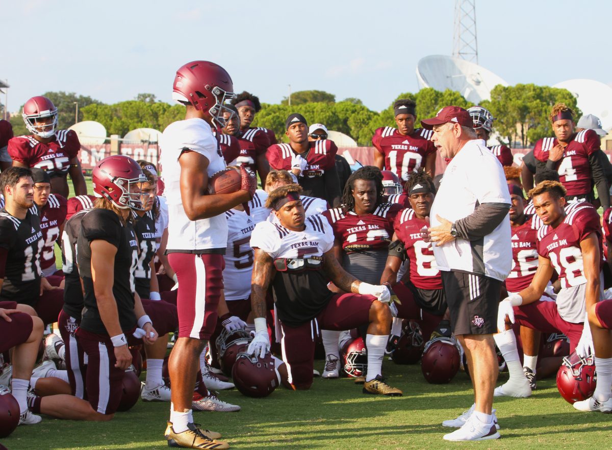 Defensive coordinator John Chavis gives the team a tackling lesson by demonstrating technique with freshman wide receiver&#160;Jhamon Ausbon.