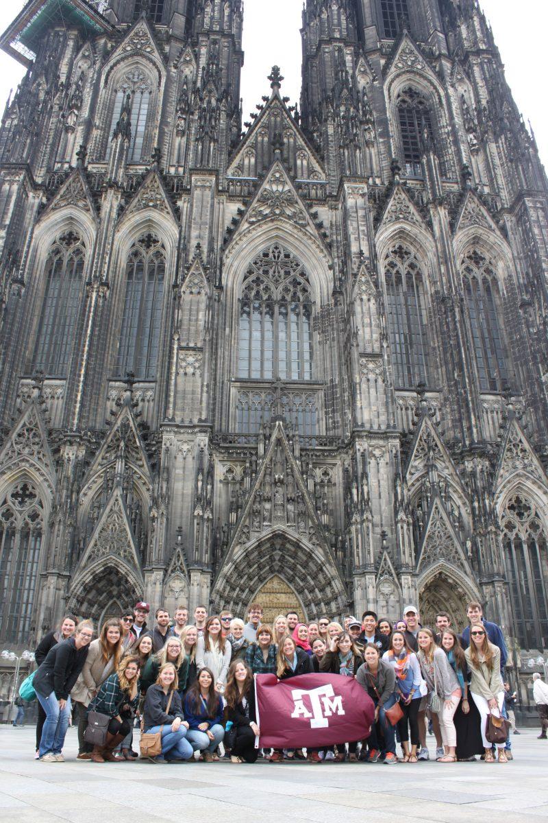 A+group+of+students+show+their+Aggie+pride+in+front+of+the+Cologne+Cathedral+in+Cologne%2C+Germany.%26%23160%3B