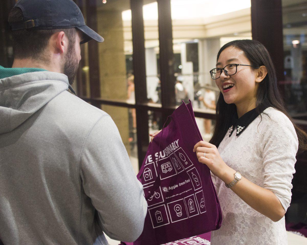 Yanpu Zhang informs students on sustainability methods while distributing reusable bags.