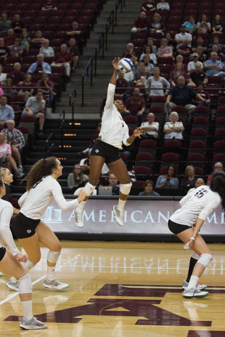 Senior Kiara McGee jumps to put the ball over the net during the second of three sets.