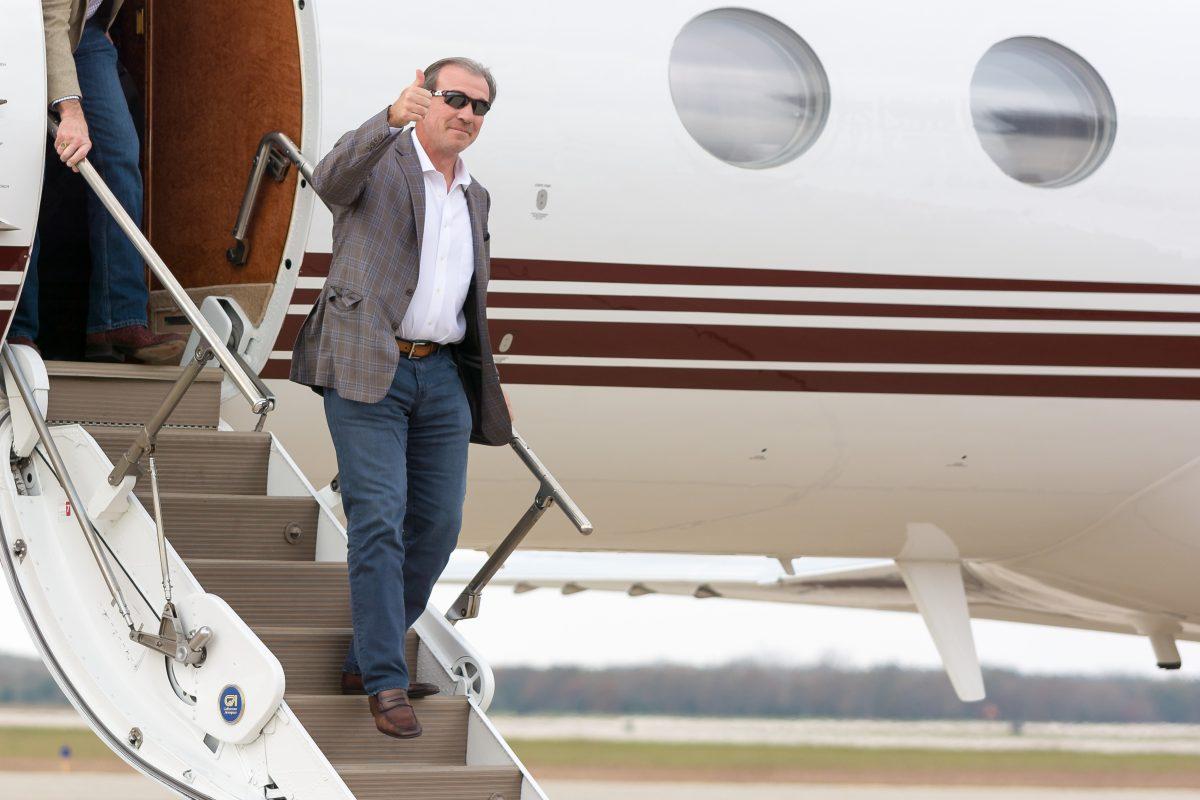 New Texas A&M head football coach Jimbo Fisher throws up a Gig em while arriving at Easterwood Airport on Sunday afternoon.