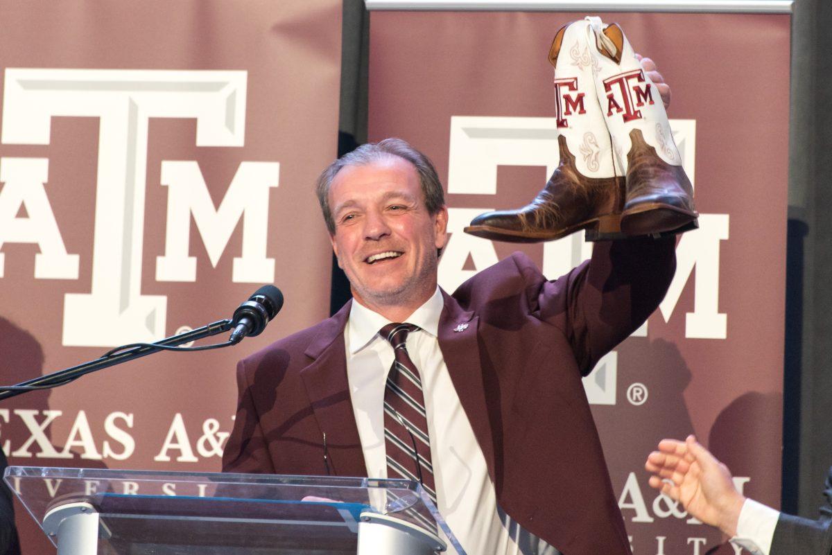 Texas A&M head coach Jimbo Fisher lifts up a pair of A&M cowboy boots that were given to him as a gift after being introduced as new head coach.