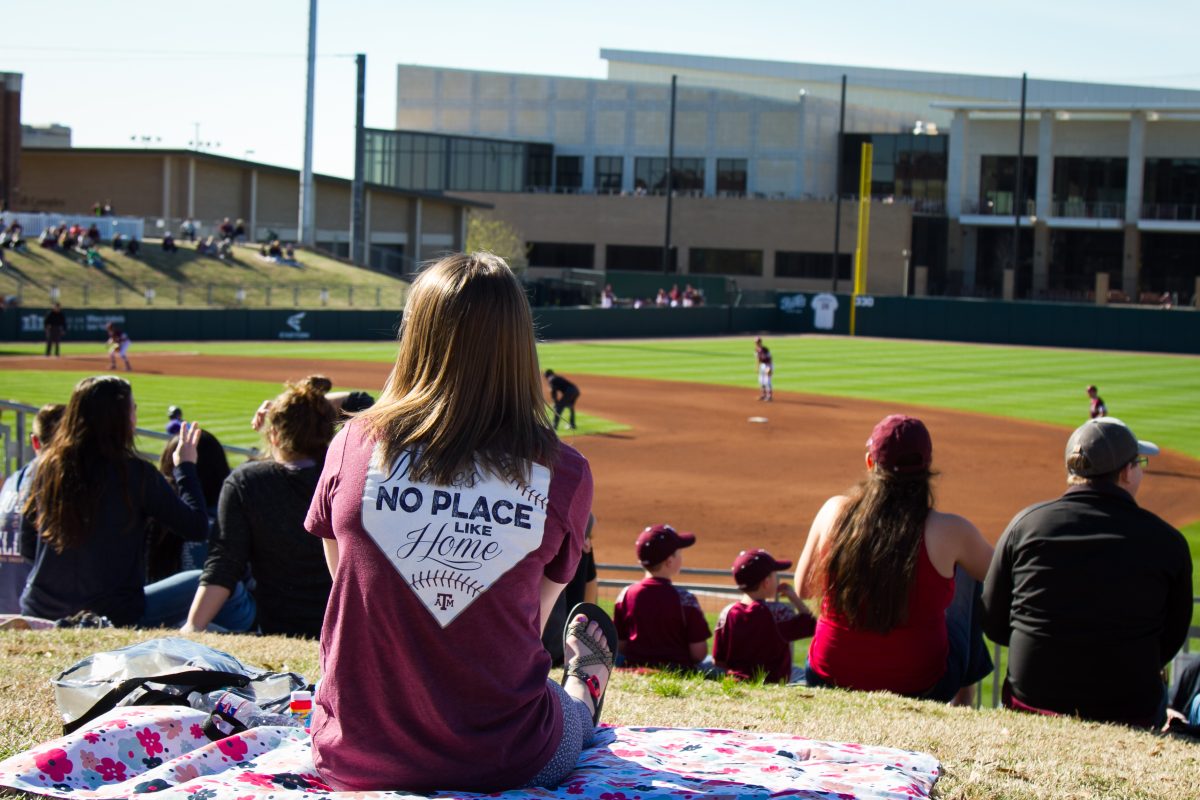 A Texas A&amp;M baseball fan watches the game from the lawn.