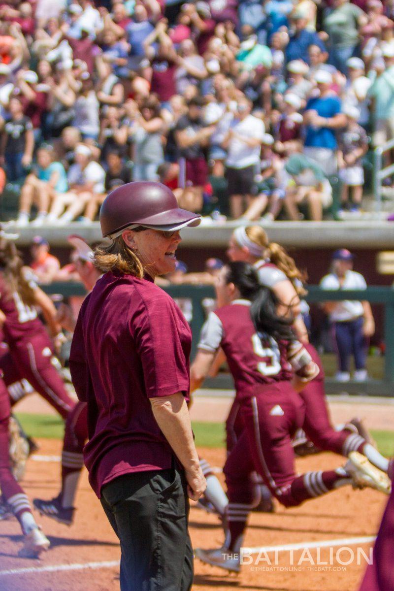 Texas A&M head coach Jo Evans watches as the team runs onto the field after the walk-off hit that gave A&M the series win.