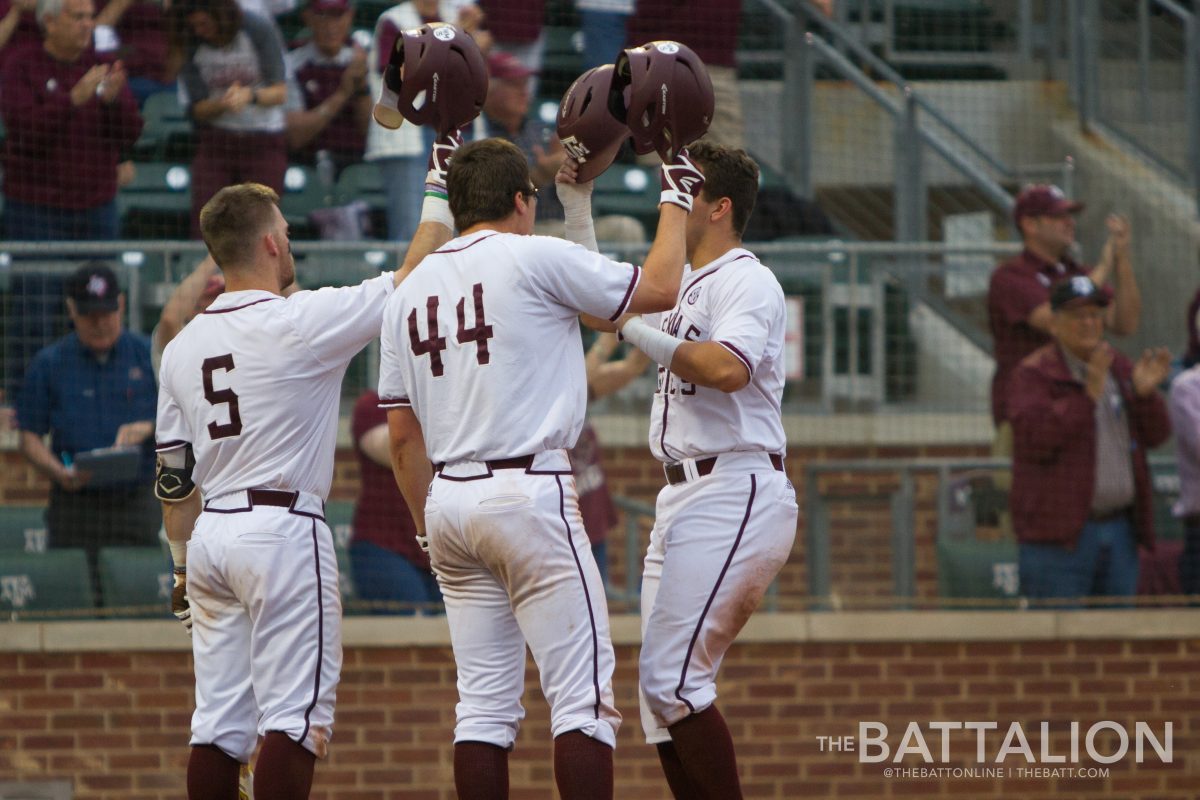 Sophomore Logan Foster and junior George Janca celebrate with sophomore Cam Blake&#160;after he scores a run for the Aggies.