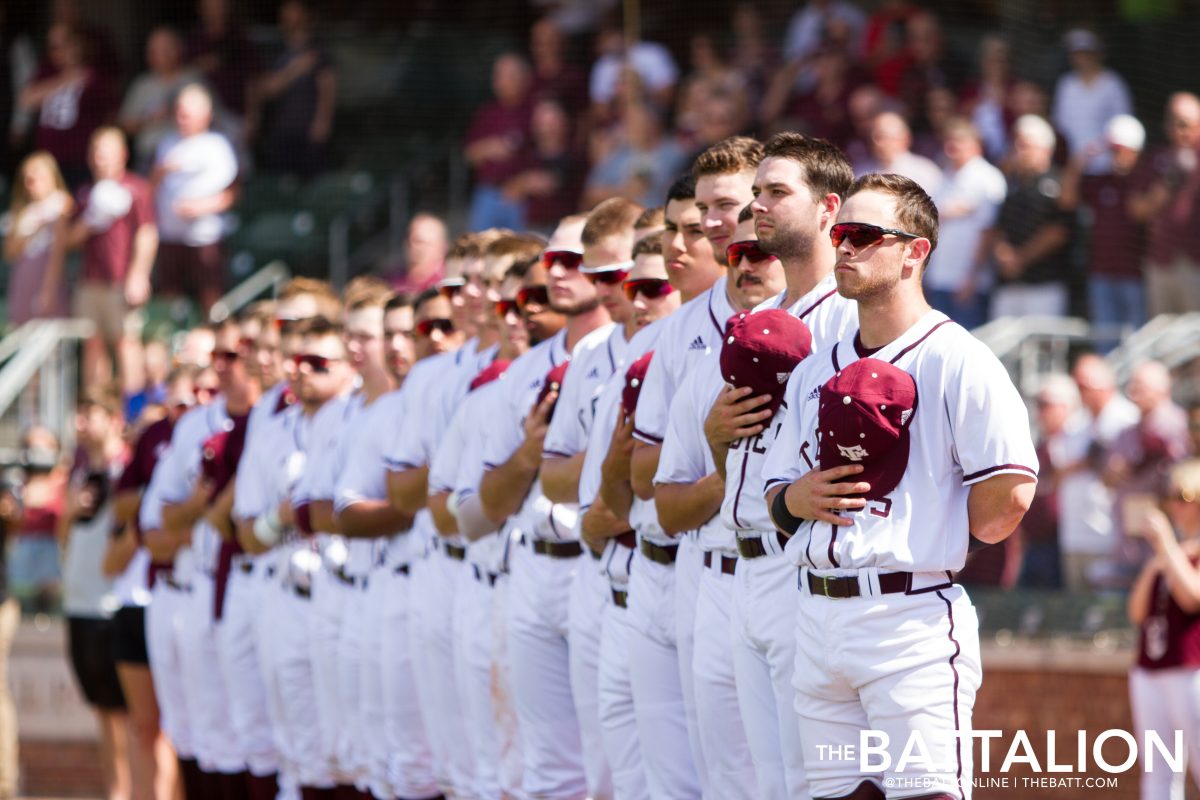 The Aggies take off their hats and look to the outfield for the United States flag during the National Anthem.