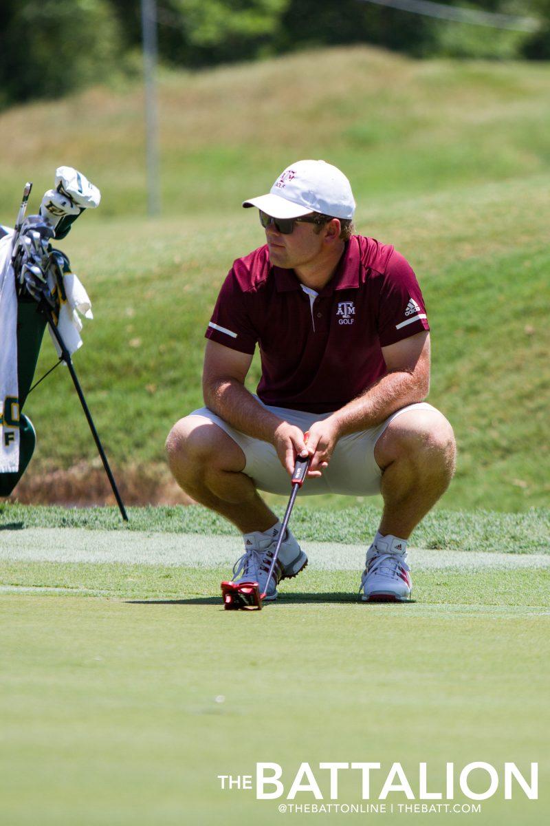 Senior Andrew Paysse looks at the slope of the green in order to putt.