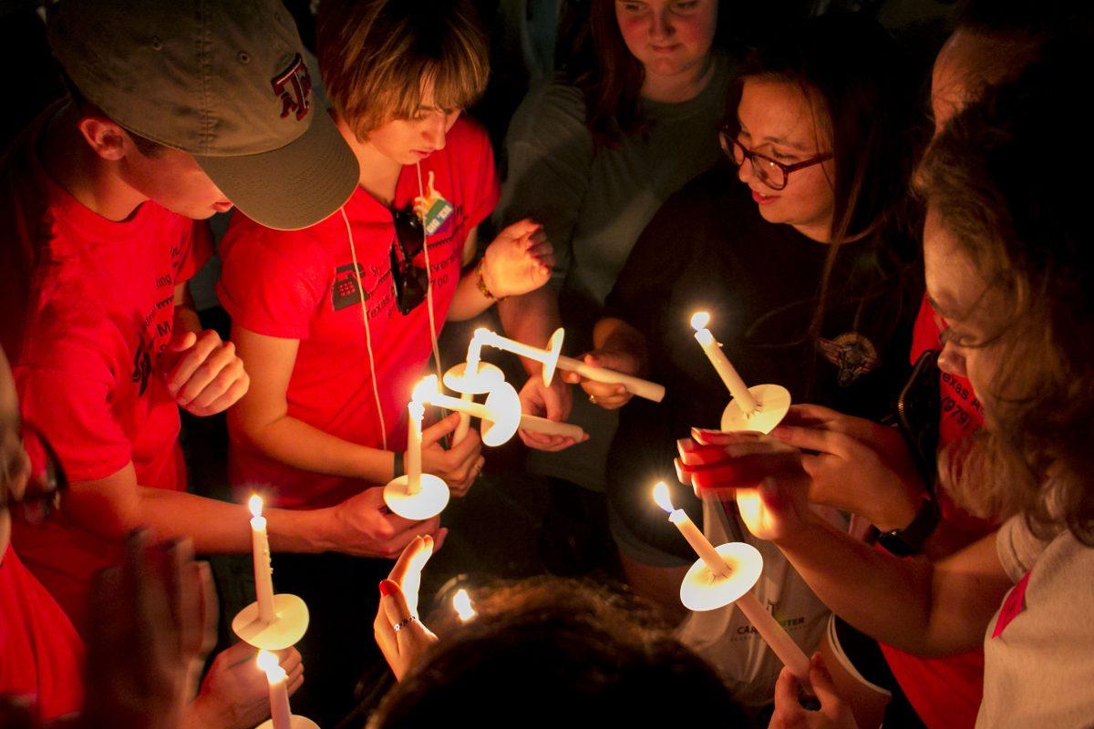 While winds blew away the flames, HelpLine Volunteers and students gathered in a close circle to keep their candles lit at the suicide awareness walk on Sept. 19.