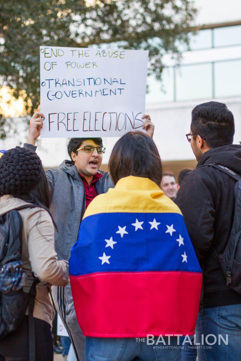 Christian Rodriguez, Class of 2018, holds up a sign while speaking to other demonstration attendees on Wednesday afternoon. The event was hosted by the Texas A&M Venezuelan Student Association to support change in the Venezuelan regime