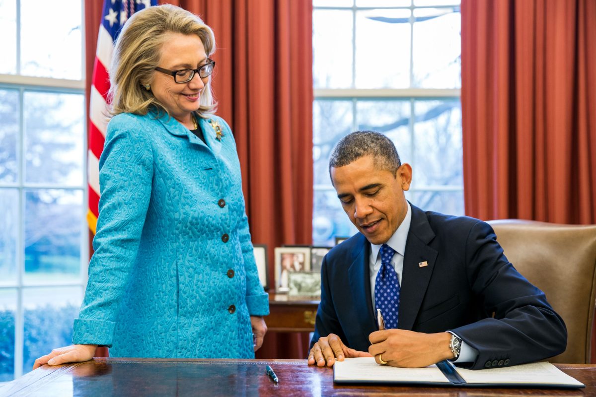 Secretary of State Hillary Clinton watches as President Barack Obama signs a  memorandum to Promote Gender Equality and Empower Women and Girls Globally Jan. 20, 2013. 