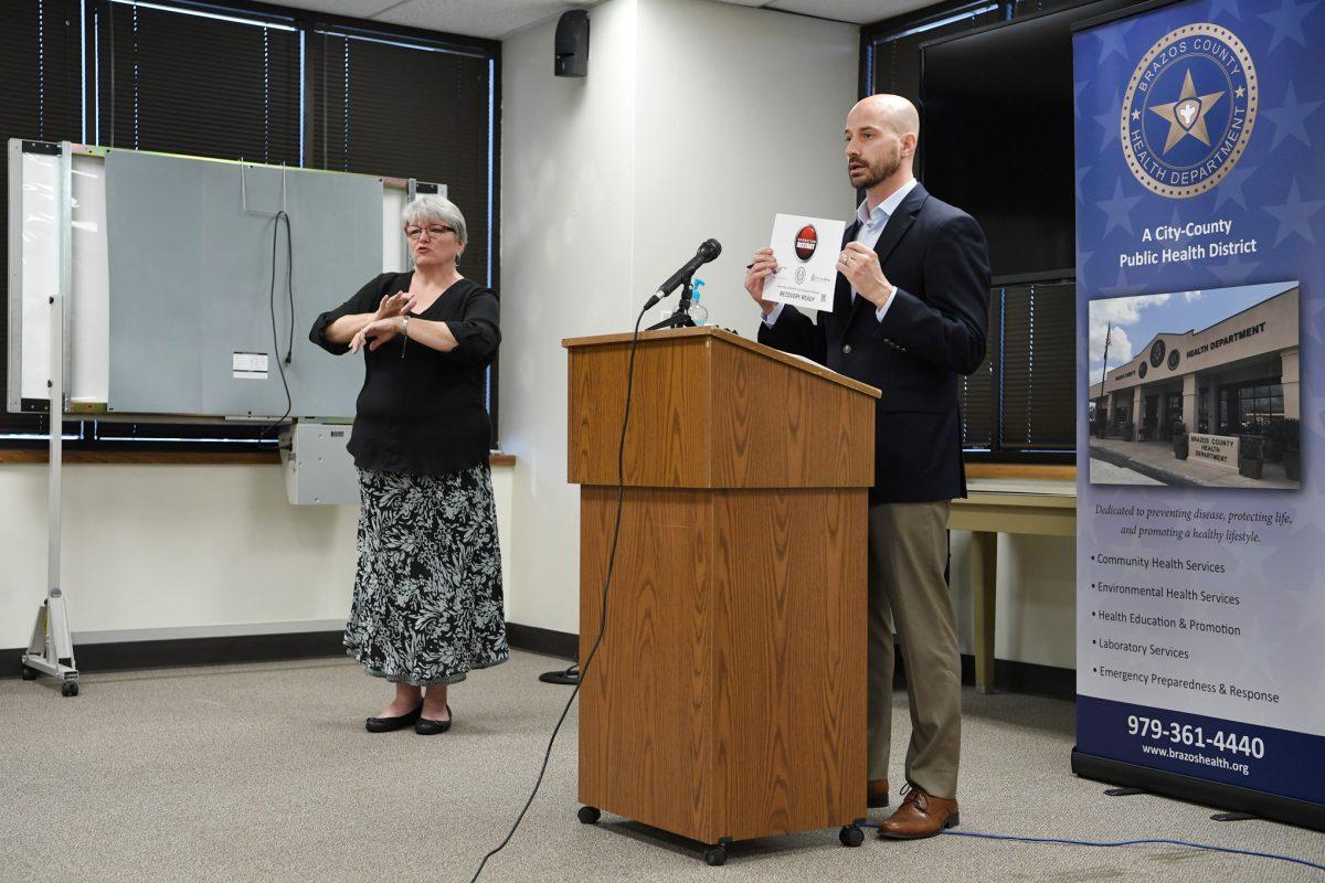 Brazos County Alternate Health Authority Dr. Seth Sullivan, right, holds an Operation Restart sign while speaking at a press conference Tuesday, May 26, 2020, beside American Sign Language interpreter Sherri Roberts.