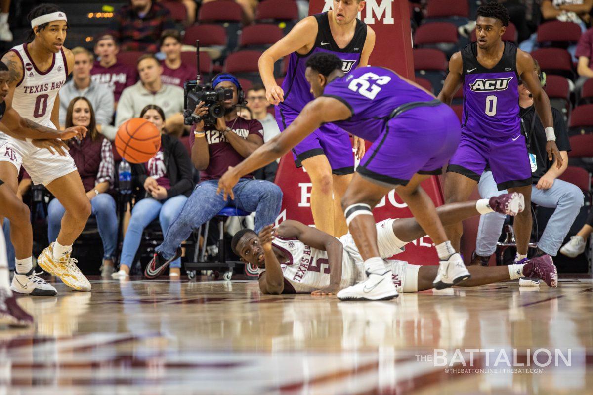 Junior guard Hassan Diarra passes the ball to his teammate after being knocked to the floor.