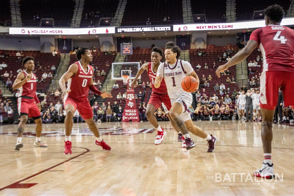 Sophomore guard Marcus Williams (1) running through Arkansas defenders to shoot a layup in the Aggies game against the Razorbacks on Saturday, Jan. 8, 2022.