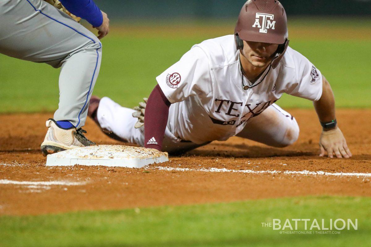 Senior catcher Troy Claunch (12) slides into first base after an attempted pickoff against Houston Baptist in Blue Bell Park on Tuesday, Mar. 1, 2022.
