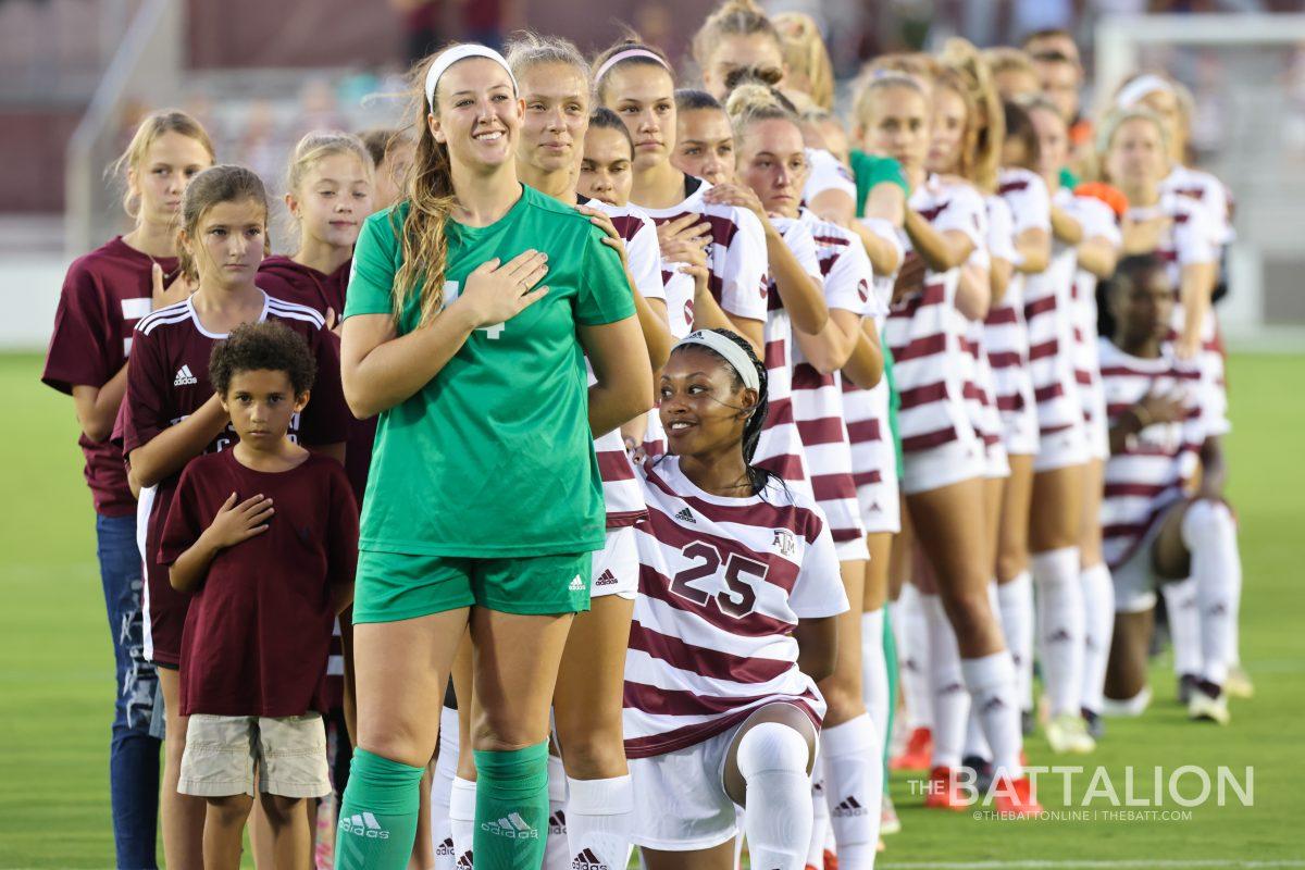 The Texas A&M soccer team stand in line during the playing of the national anthem. 