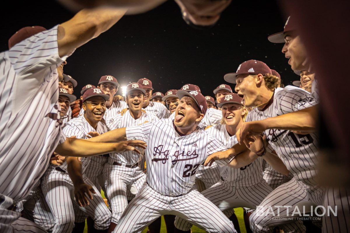 Junior pitcher Micah Dallas (34) gives a Pringle to A&M coach Jim Schlossnagle (22) in celebration ater the Aggies outlast the Razorbacks at Olsen Field on Friday, April 22, 2022.