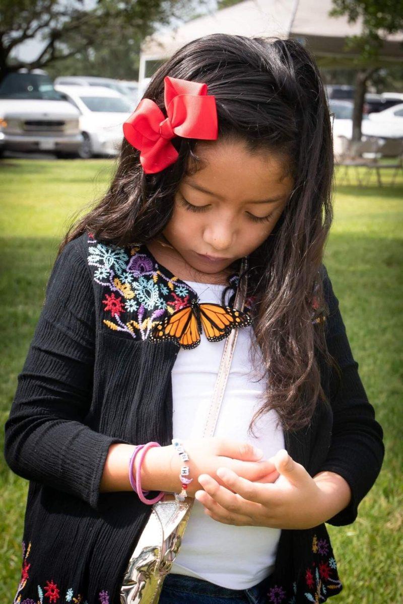 A young girl watches as a butterfly walks along her shirt at the Wish Upon a Butterfly farm, part of the Brazos Valley Museum of Natural History.