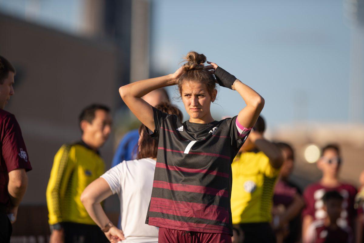 <p>Senior D Katie Smith (7) ties back her hair before the game in Ellis Field on Thursday, Aug. 25, 2022.</p>