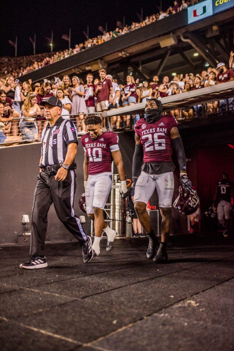 Two Texas A&M players walk out with the ref to do the coin toss at Kyle Field.