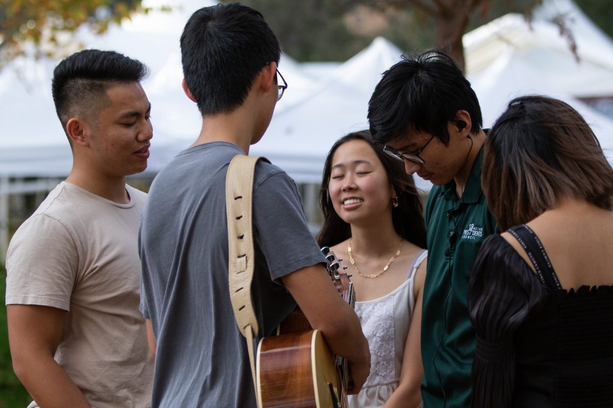 Members of Stinters, an event coordinator and singer Sorah An pray before ADIPA City Limits in Aggie Park on Thursday, Nov. 3, 2022.