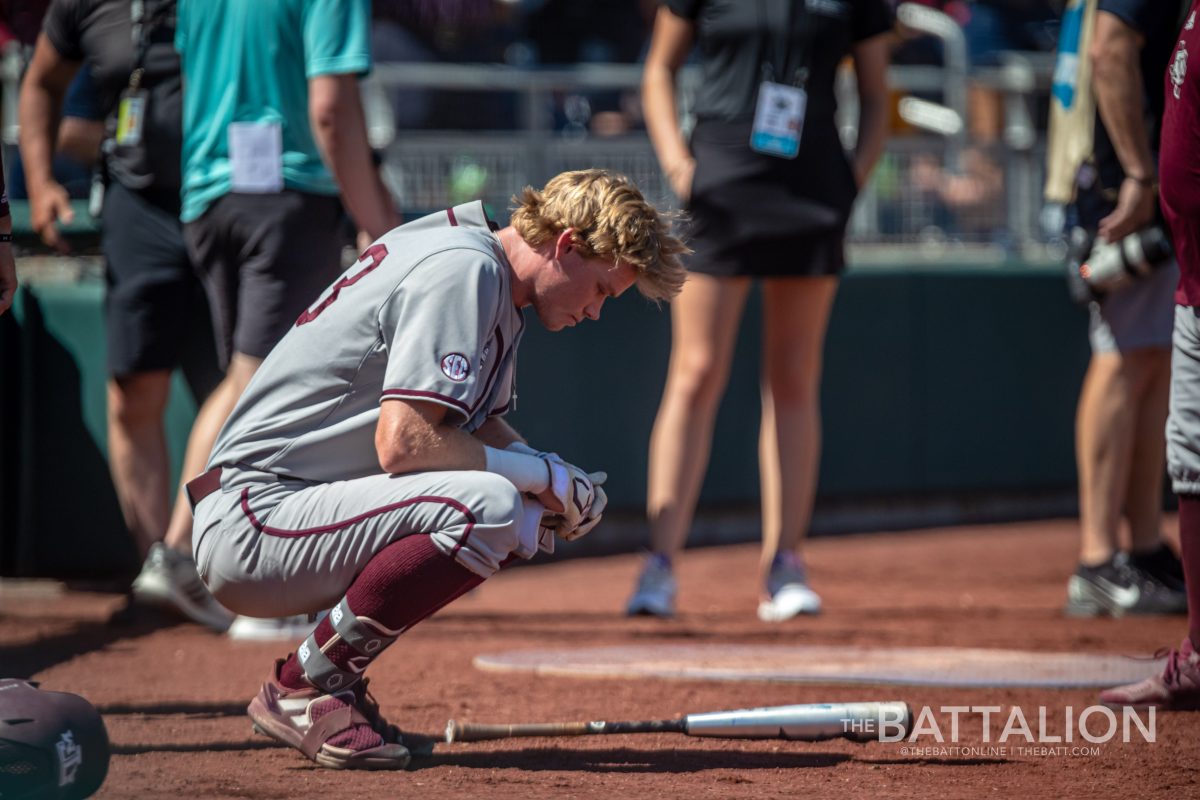 Junior RF Brett Minnich (23) sits on the track after striking out in the top of the ninth inning to end the Aggies run in the Mens College World Series at Charles Schwab Field in Omaha, Nebraska on Wednesday, June 22, 2022.