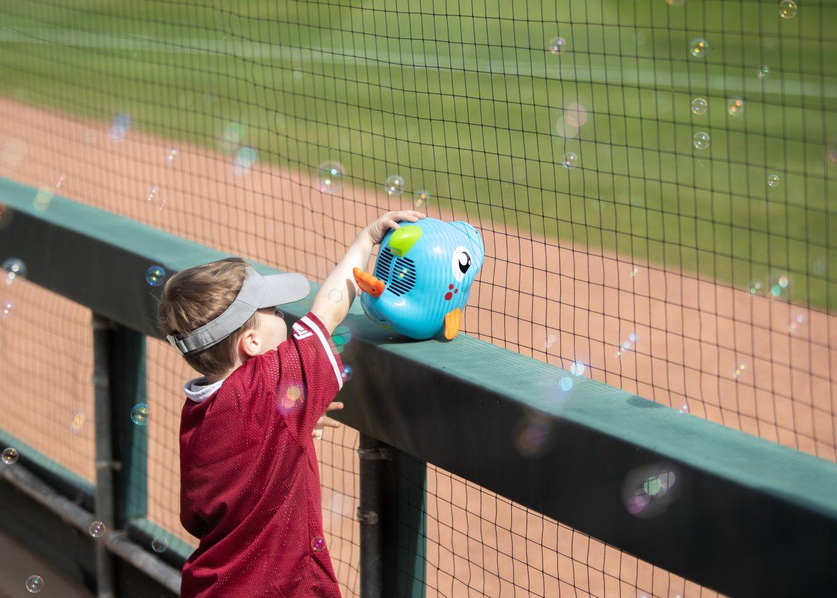 A child celebrates a scored run with bubbles against Seattle U at Blue Bell Park on Sunday, Feb. 19, 2023.