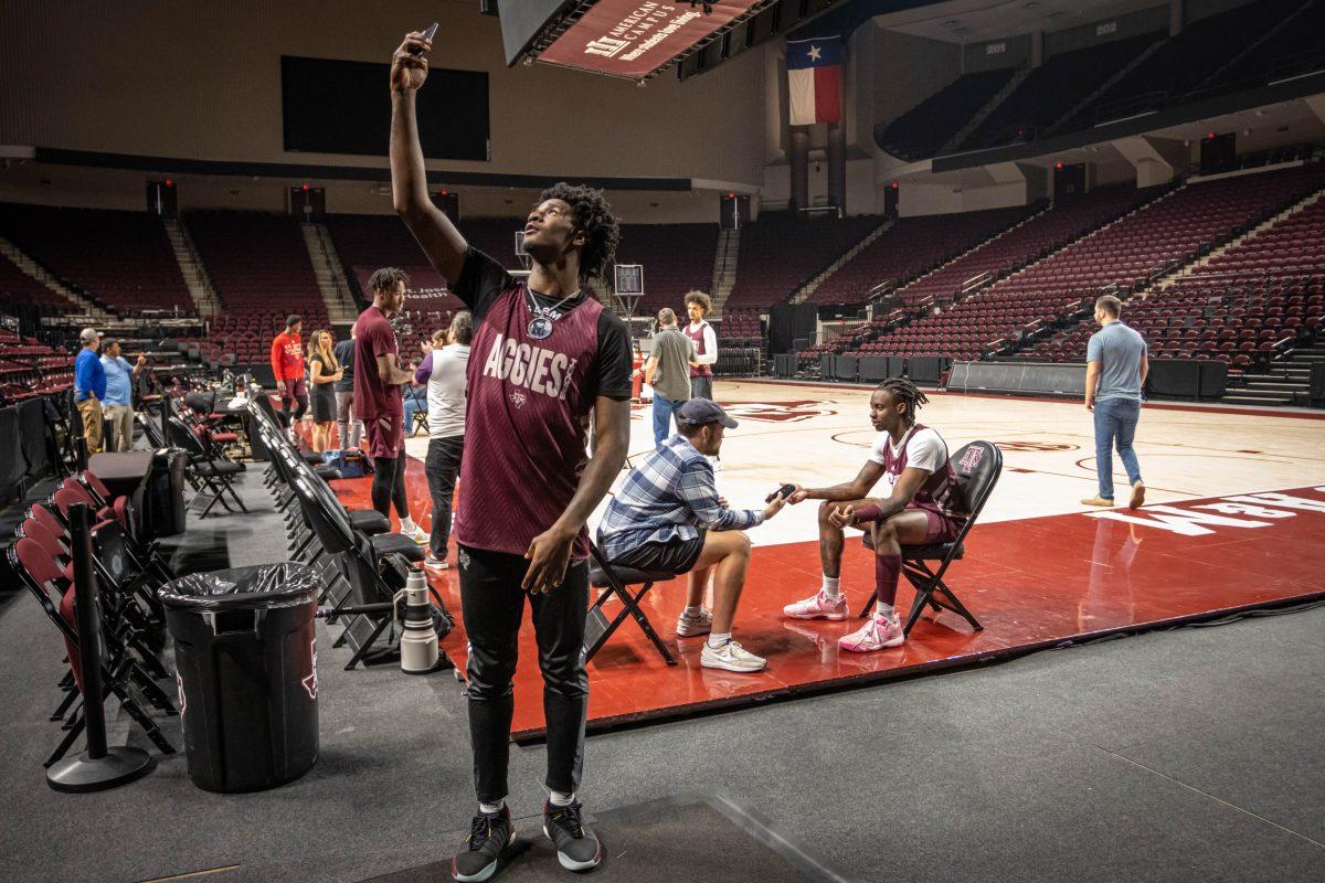 Freshman F Solomon Washington (13) takes a selfie while sports editor Grant Gaspard talks to sophomore G Manny Obaseki (35) during media availability on Tuesday, March 7, 2023.