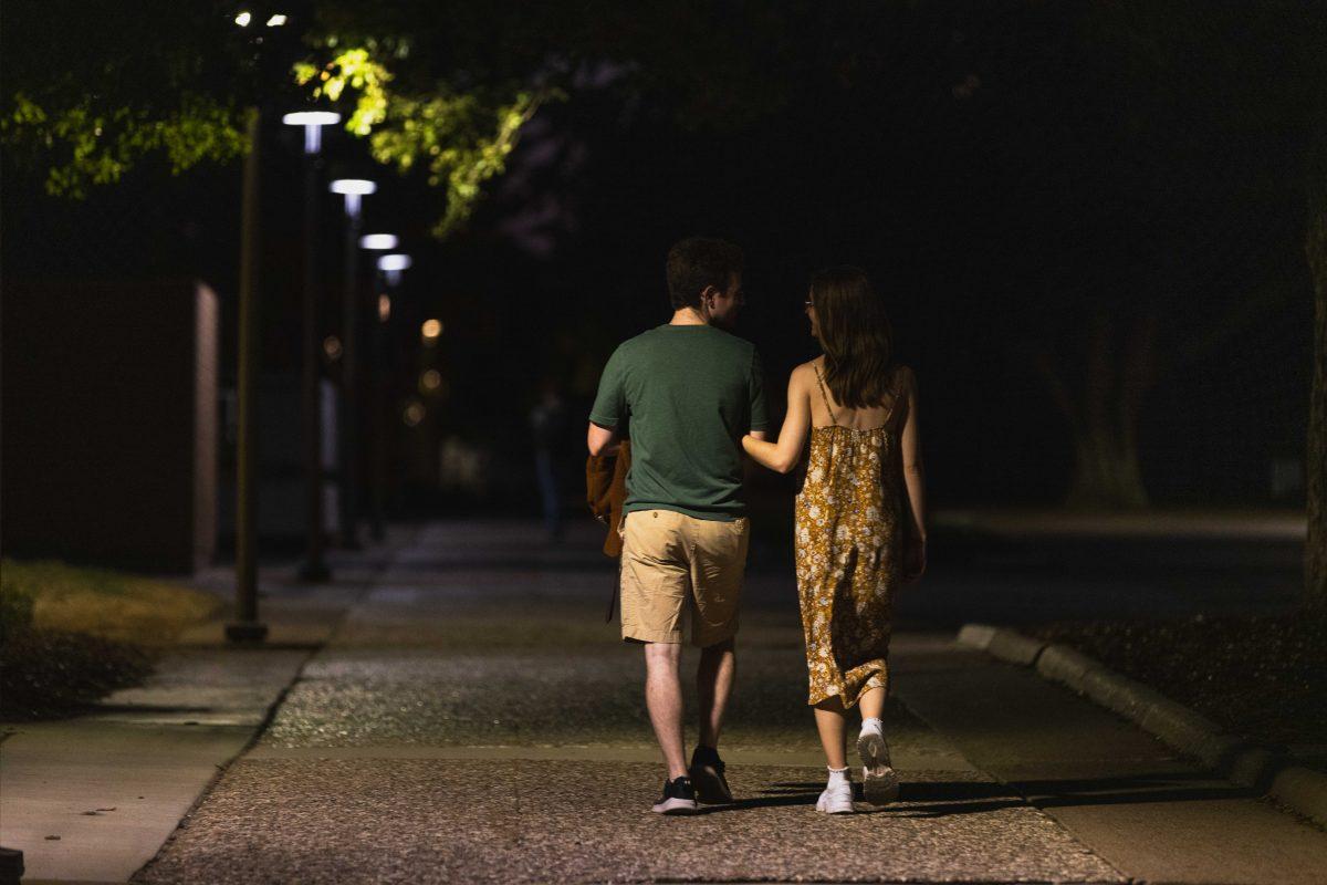 <p>Students holding hands while walking in front of Evans library on Friday evening, September 22, 2023</p>