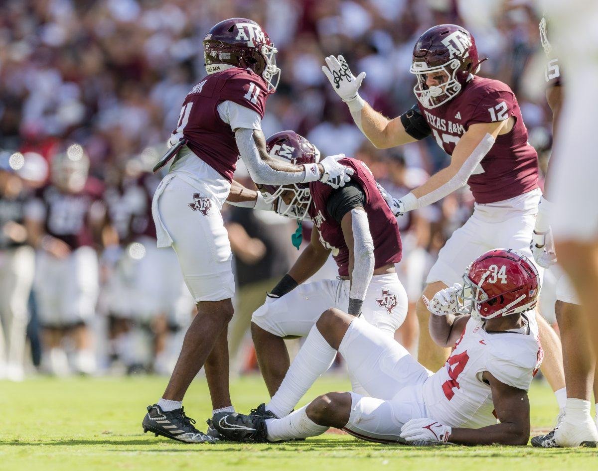 Freshman WR Raymond Cottrell (11) anf graduate LB Sam Mathews (12) help graduate LB Ainias Smith (0) up after his run during Texas A&Ms game against Alabama on Saturday, Oct. 7, 2023. (Ishika Samant/The Battalion)