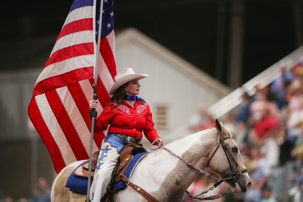 The American Flag is held at the beginning of every rodeo session as the crowd says a prayer and sings the National Anthem. (Ishika Samant/The Battalion)