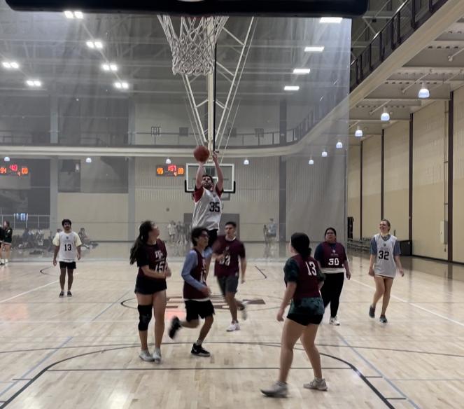 Biomedical sciences senior Farris Safadi of Family Part 2 makes a three-pointer on a fast break in the fourth quarter against SHPE in the coed rec basketball league Feb. 25 at the Student Rec Center. (Photo by Ethan Brown, JOUR 359 contributor)