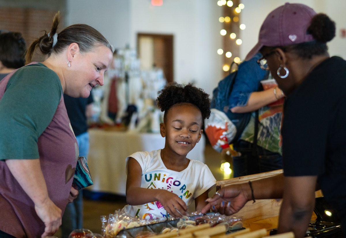 Candace Sampson, owner of Candaces Cookie Shop, and her daughter talk to a customer at Lovers Market on Saturday, Feb. 3, 2024 in Ice House, Downtown Bryan.