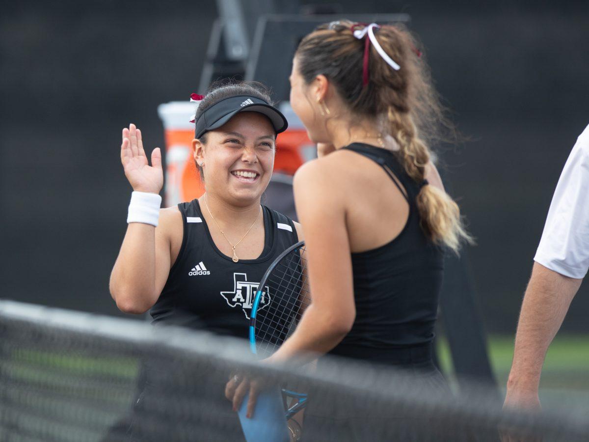 Freshman Lucciana Perez smiling at doubles partner Junior Jeanette Mireles during Texas A&Ms game against SMU on Tuesday, Feb. 27, 2024 at Mitchell Tennis Center. (Hannah Harrison/The Battalion)