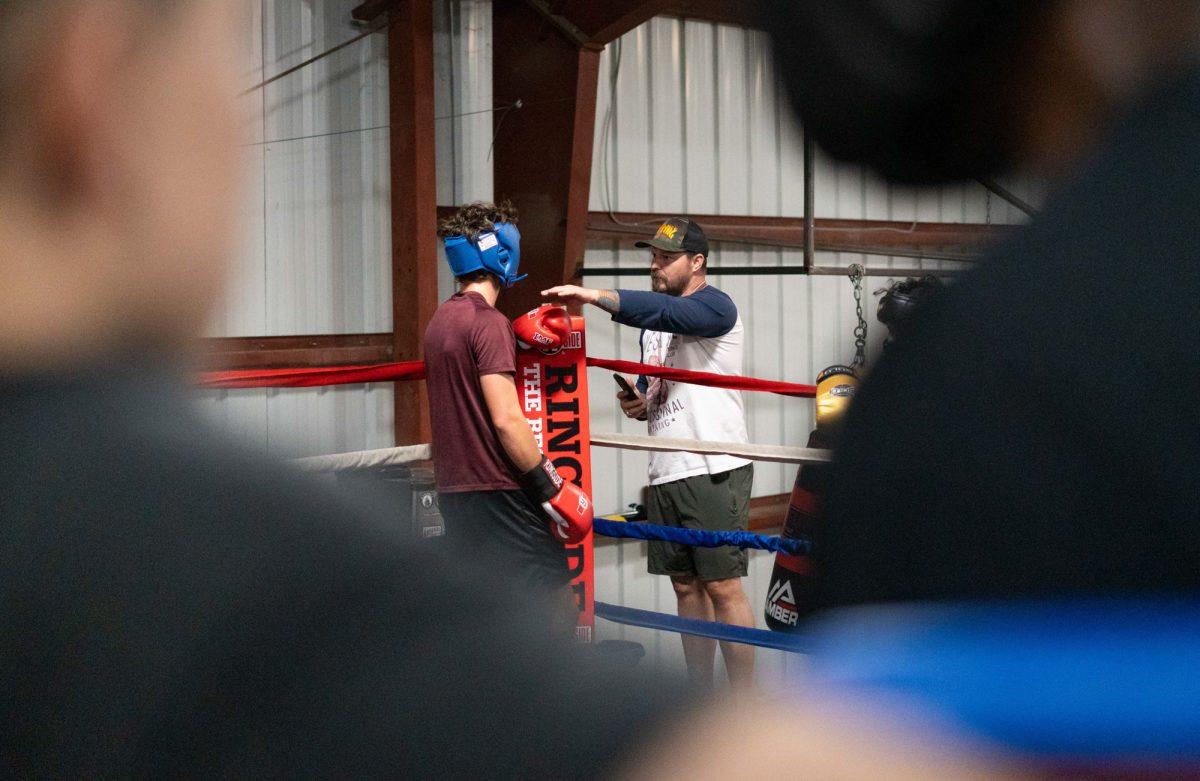 The blue corner watches as BCS Boxing owner and coach Carl Perry coaches fighter Staddler Kirsten in the red corner during Farmers Fight Night sparring practice on Thursday, March. 7, 2024, at BCS Boxing Club.