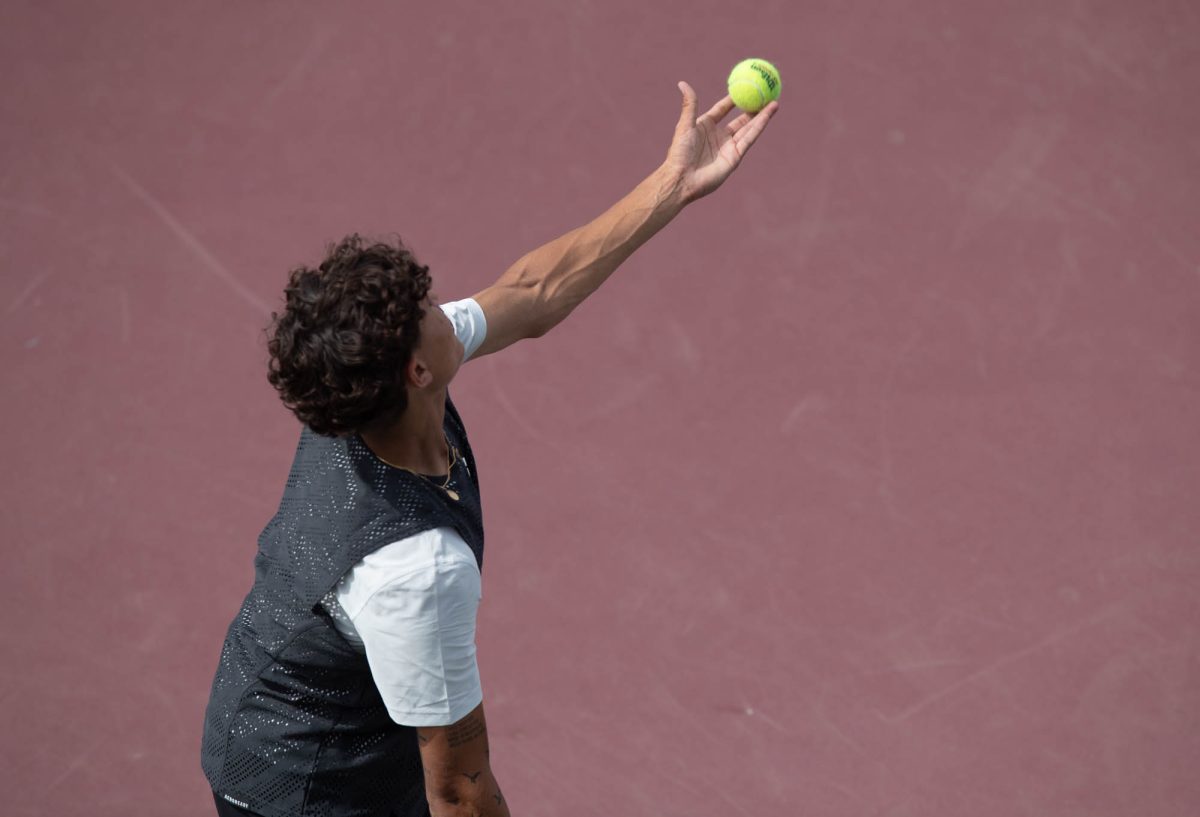 Freshman Tiago Pires throws the ball up to serve the ball during Texas A&M’s match against Arkansas on Sunday, April 7, 2024 at Mitchell Tennis Center. (Lana Cheatham/The Battalion)