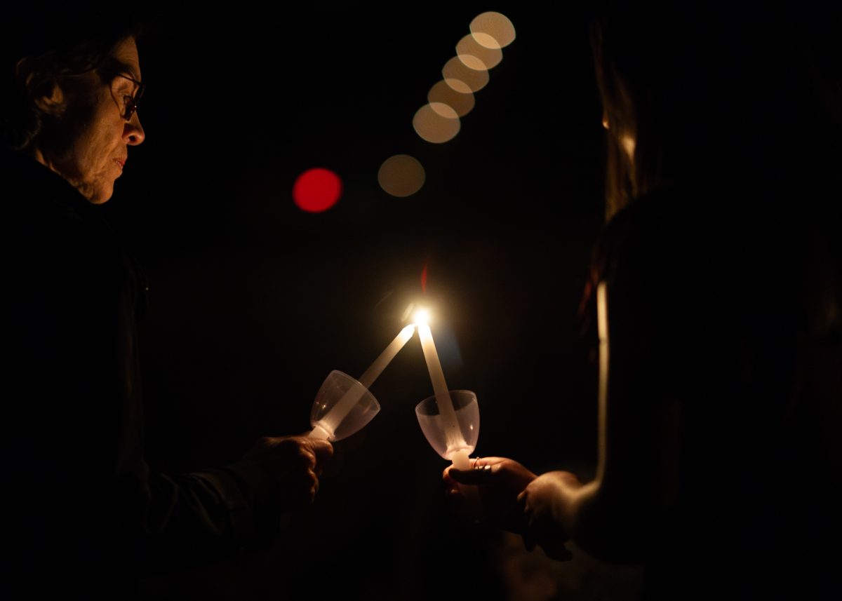 Candleholders exchange flames during the Muster ceremony in Reed Arena on Sunday, April 21, 2024. (Kyle Heise/The Battalion)