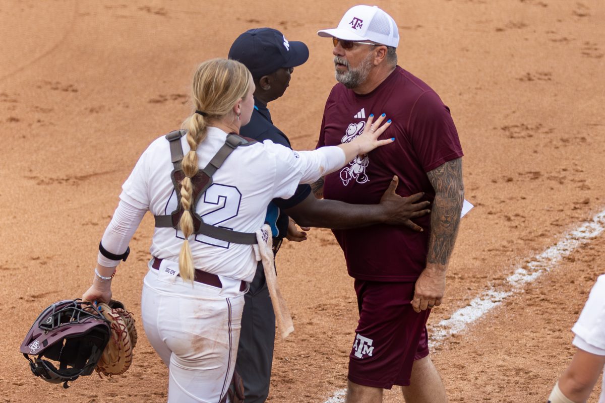 Texas A&M catcher Julia Cottrill (42) and an umpire restrain Texas A&M assistant coach Russ Heffley during Texas A&M’s game against Texas at the Austin Super Regional at Red and Charline McCombs Field in Austin, Texas, on Friday, May 24, 2024. (CJ Smith/The Battalion)