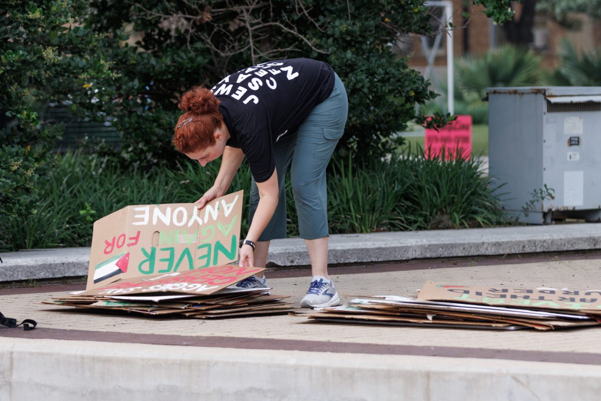 A demostrator sorts through some placards after the free Palestine protest on Tuesday May 7, 2024. (Samuel Falade/The Battalion)