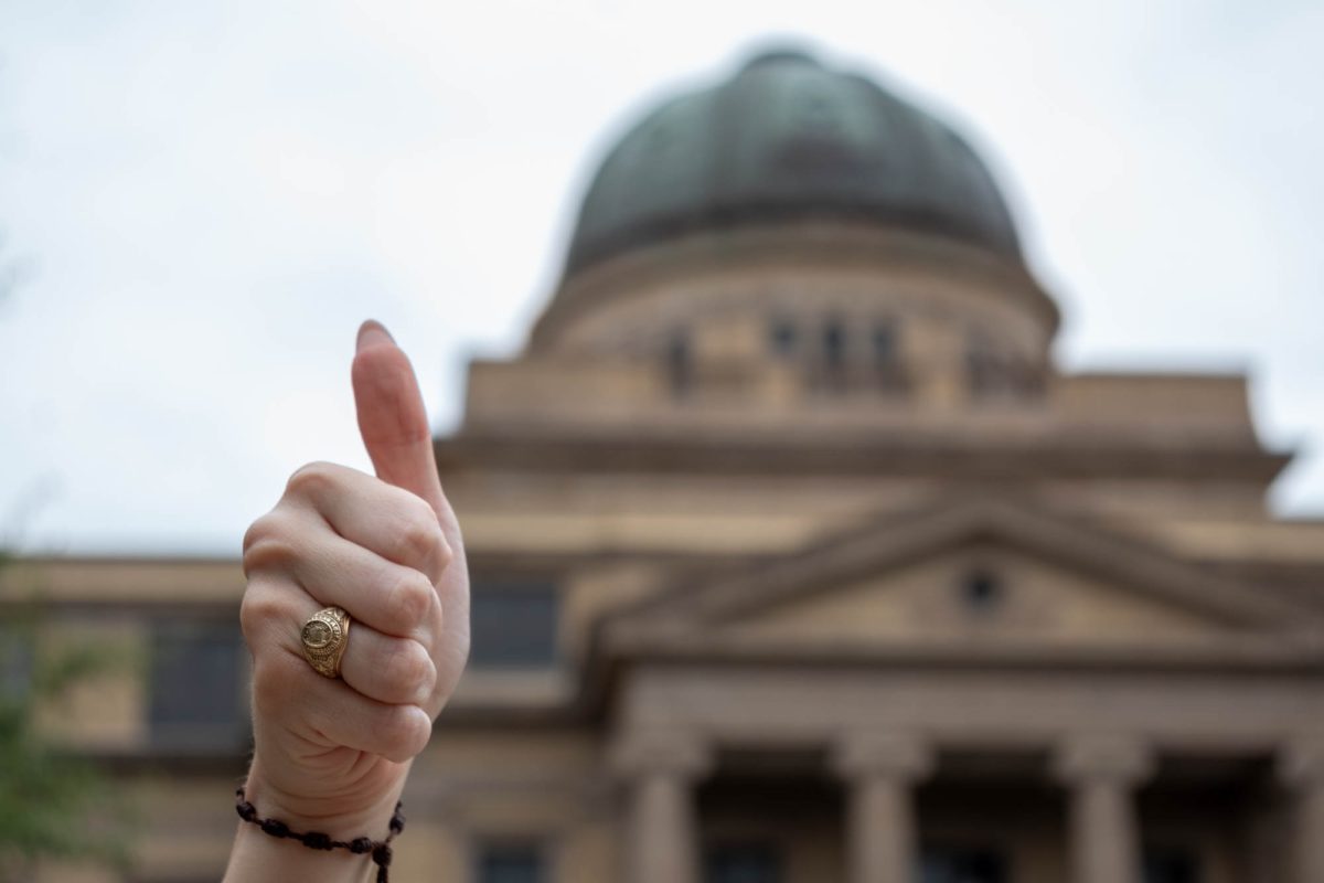 An Aggie throws a Gig 'Em in front of the Academic Building in Academic Plaza on Thursday, Sept. 12, 2024. (Isabel Lubrano/The Battalion)