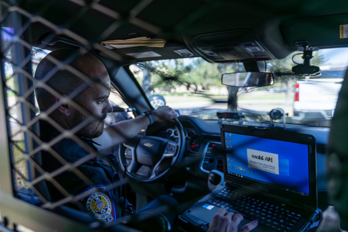 Officer Durr poses for a photo inside a police car on Tuesday, Oct. 1, 2024. (Jackson Stanley/The Battalion)