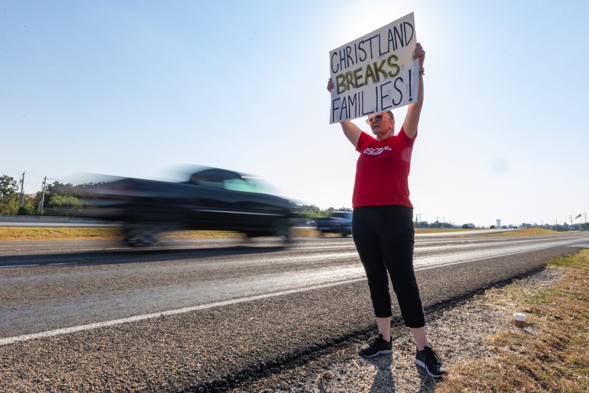 Katherine Hunter holds a sign on the side of the road in protest against the alleged abuse by the Christland Church off Highway 6 on Saturday, Oct. 12, 2024. (Chris Swann/The Battalion)