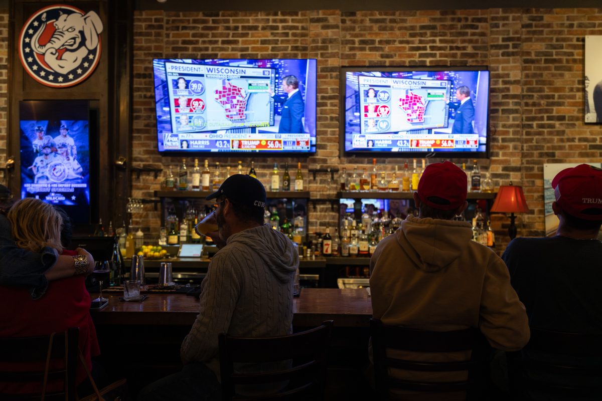 Attendees watch the TVs at the bar as election results come in during a watch party hosted at The Angry Elephant.