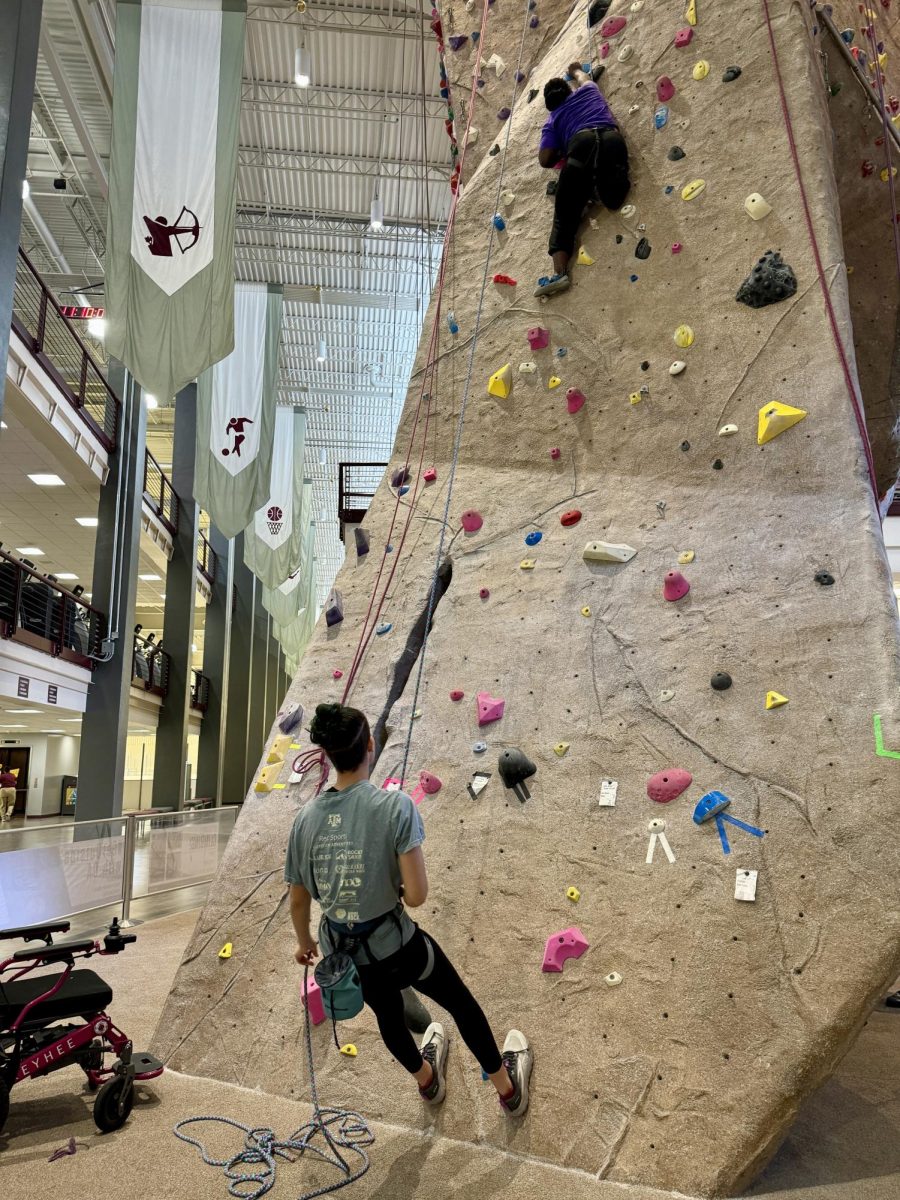 Meteorology senior and adaptive climbing clinic founder Sierra Hill assisting neuroscience sophomore Divine Favor
Akinbobola on the wall.